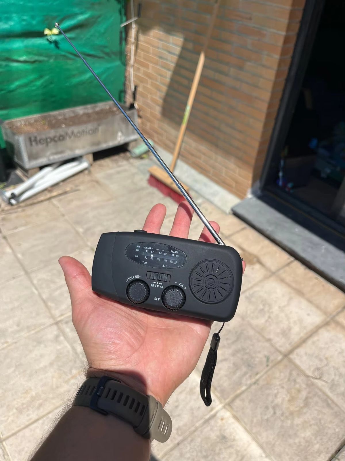 Wind-up emergency radio held in one hand, antenna up